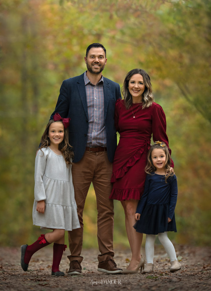 beautiful family with two young girls in nature outdoor fine art portrait in coordinating fall colors